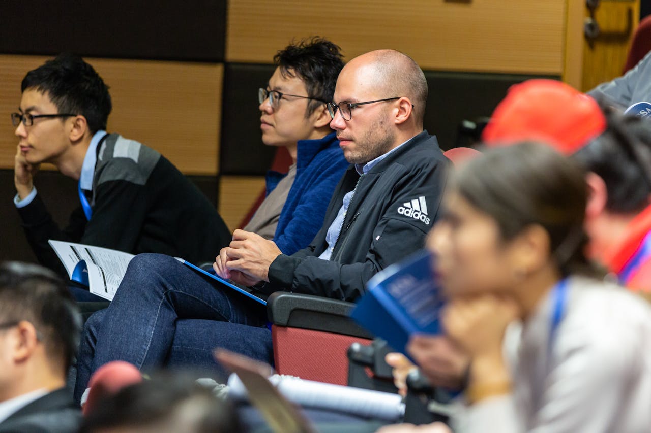 knight-hennessy-scholarship-man-wearing-black-adidas-jacket-sitting-on-chair-near-another-man-wearing-blue-jacket