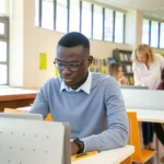 GREAT Scholarships smart-young-ethnic-guy-browsing-laptop-during-lesson-in-university-