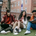 International Leadership cheerful-multiethnic-students-with-books-sitting-near-university