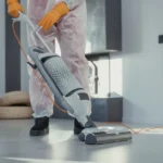 a housekeeper/cleaners job man-using-a-vacuum-on-floor-tiles