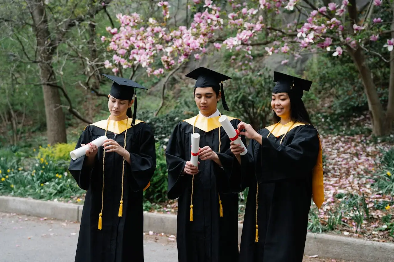 utrecht excellence scholarship students-in-graduation-gowns-and-hats-unfolding-certificates-and-magnolia-in-background