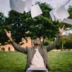 excited BI presidential scholarship male-student-throwing-university-papers-in-air