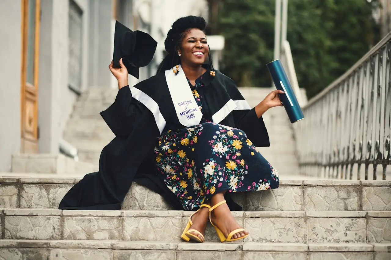 a fellowship award-woman-wearing-academic-dress-and-floral-dress-sitting-on-stairway